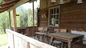 A rustic wooden cabin with a porch, wooden furniture, and a view of the forest. - Chalet Near Lake Klopeiner With Sauna (Feistritz ob Bleiburg)