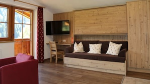 A cozy room with a wooden sofa, a television, and a desk with a chair. - Spacious Chalet near Ski Area in Saalbach-Hinterglemm (Viehhofen)