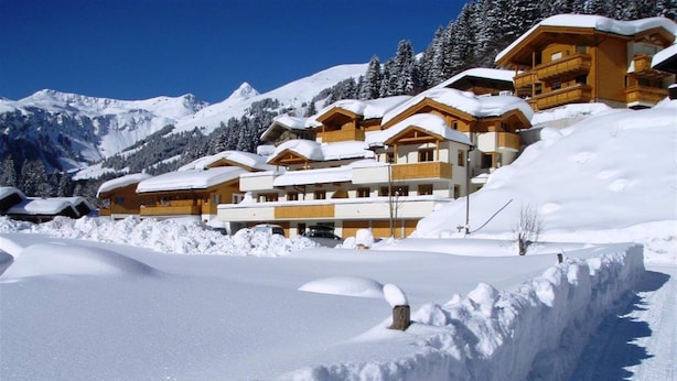 Une station de montagne enneigée, avec des bâtiments en bois et un ciel dégagé.