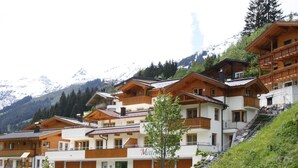 Un ensemble de bâtiments de style chalet en bois, dotés de balcons, se dressant sur un fond de montagnes enneigées.
