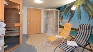 A room with a sauna, a massage chair, a glass-enclosed shower, and a beach-themed mural. - Apartment in Burg Reuland With Forest (Burg-Reuland)