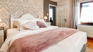 Una camera da letto con un letto, un comodino, una lampada, un armadio e una finestra con tende.