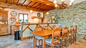 Una cucina rustica con travi in legno, un muro in pietra e un'area pranzo con sedie e tavolo in legno.