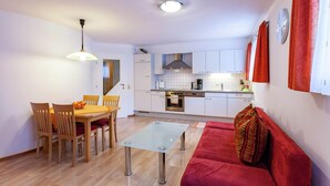 A compact living space with a dining area, kitchenette, and a red sofa. - Cozy Holiday Home in Vandans near Montafon Ski Area (Vandans)
