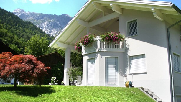 A white building with a balcony, a staircase, and a view of mountains. - Cozy Holiday Home in Vandans near Montafon Ski Area (Vandans)