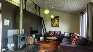 A modern living room with a fireplace, a sofa, a rug, and a television. - Boutique Chalet in Büllingen near Lake (Buellingen)