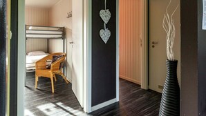 A room with a bunk bed, a wicker chair, and a decorative wall hanging. - Boutique Chalet in Büllingen near Lake (Buellingen)