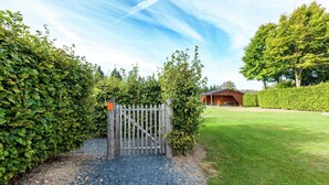 A gated entrance with a gravel path leading to a building with a sloped roof. - Boutique Chalet in Büllingen near Lake (Buellingen)