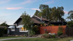 A modern house with a dark exterior, a wooden fence, and a well-maintained garden. - Palm Cottage San Diego (La Mesa)