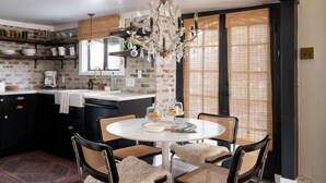 A kitchen with a round dining table, black cabinets, and a chandelier. - Palm Cottage San Diego (La Mesa)