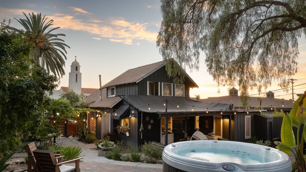 A house with a hot tub, outdoor seating, and a view of a church. - Palm Cottage San Diego (La Mesa)