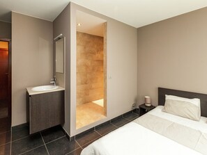 A modern hotel room with a large bed, a bathroom with a sink and mirror, and a walk-in shower. - Beautiful Villa with Sauna & Hot Tub in the Region Haspengouw (Heers)