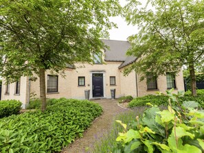 A brick house with a dark door, surrounded by lush greenery and a brick pathway. - Beautiful Villa with Sauna & Hot Tub in the Region Haspengouw (Heers)