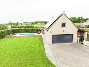 A house with a large garage, a swimming pool, and a well-maintained lawn. - Beautiful Villa with Sauna & Hot Tub in the Region Haspengouw (Heers)