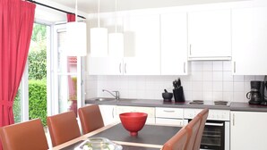 Eine moderne Küche mit weißen Schränken, einer schwarzen Arbeitsplatte und einer roten Schüssel auf dem Tisch.