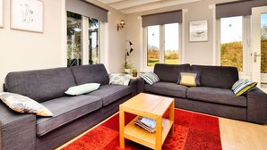 A living room with two grey sofas, a wooden coffee table, and a red patterned rug. - Family Retreat With Garden (Tenneville)