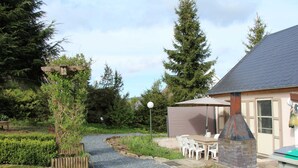 A garden with a gravel path, wooden fence, and a patio area with chairs and a table. - Family Retreat With Garden (Tenneville)