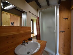 Casa de banho com toucador de madeira, lavatório branco e zona de duche.