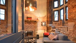 Ein gemütliches Wohnzimmer mit Kamin, einer Couch und einem modernen Kronleuchter.