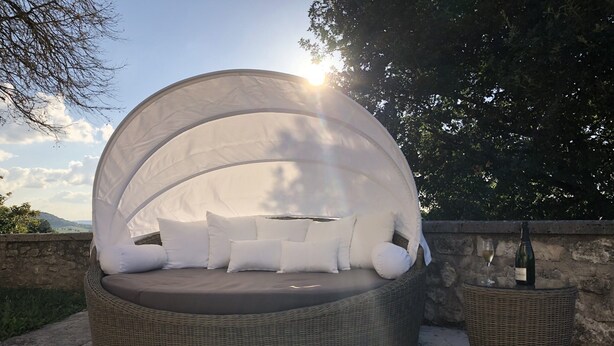 A round wicker sofa with a white canopy, a glass of white wine, and a bottle on a wicker table. - Cottage in Wine Country (Tournon-d'Agenais)