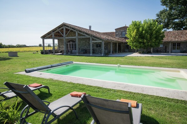 A pool with lounge chairs, a covered patio, and a stone building with a tiled roof. - Mansion in Fargues With Pool and Garden (Fargues-sur-Ourbise)
