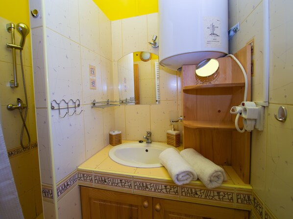 A bathroom with a sink, mirror, towel rack, and shower. - Drevenice Oscadnica (Oscadnica)