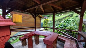 A wooden gazebo with a picnic table and benches, surrounded by lush greenery and a wooden fence. - Drevenice Oscadnica (Oscadnica)