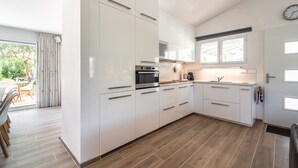 A modern kitchen with white cabinets, a built-in oven, and a window above the sink. - Villa in Pouzols With Private Pool & Vineyards (Pouzols-Minervois)