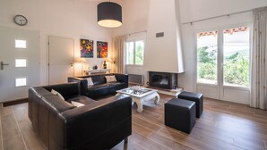 A spacious living room with a fireplace, leather sofas, a coffee table, and large windows. - Villa in Pouzols With Private Pool & Vineyards (Pouzols-Minervois)