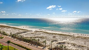Een strand met een verharde promenade, palmbomen en helder uitzicht op de oceaan.