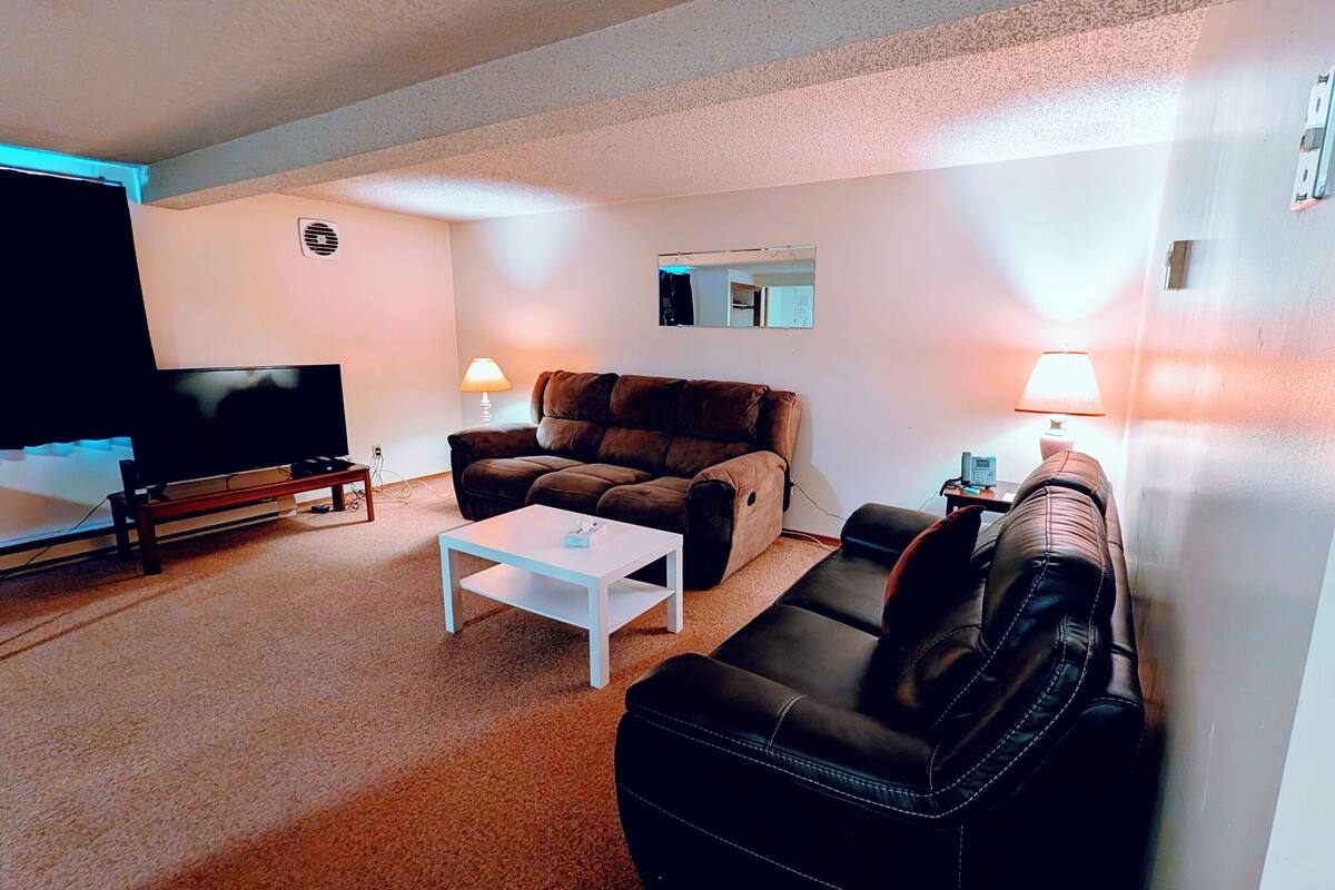 Uma sala de estar com televisão de tela plana, sofá, mesa de centro e duas luminárias.