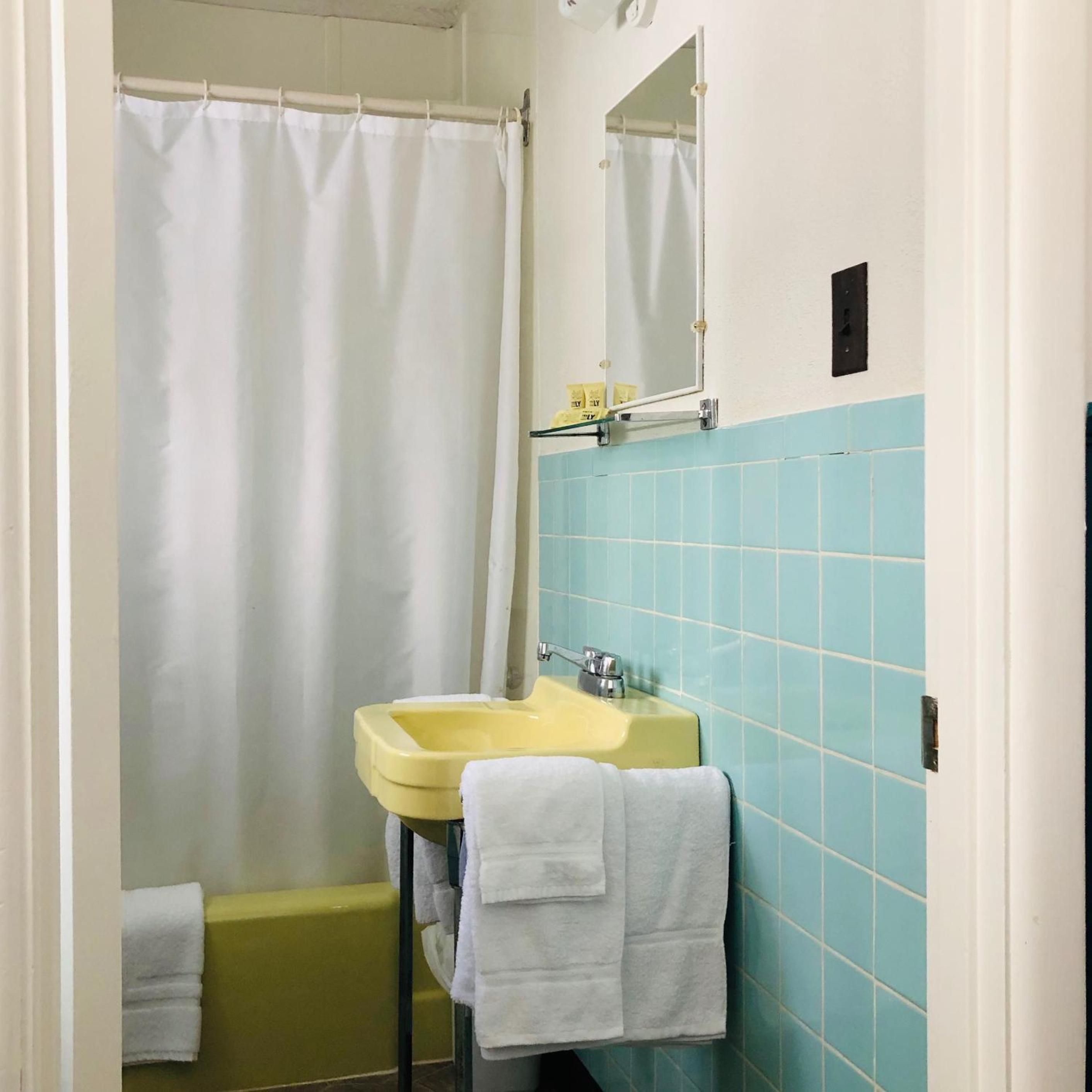 Une salle de bain avec un lavabo jaune, une baignoire et un rideau de douche.