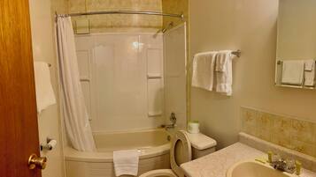 Une salle de bain équipée d’une baignoire, de toilettes, d’un lavabo et d’un rideau de douche.