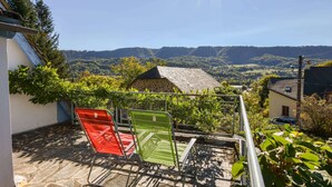 A balcony with a view of a valley, a stone wall, and a metal railing. - Vic-sur-cere Family Nest (Vic-sur-Cere)