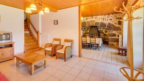 A wooden-floored living room with a fireplace, a dining area, and a staircase. - Vic-sur-cere Family Nest (Vic-sur-Cere)