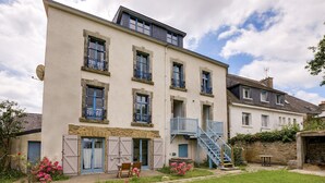 Un edificio a più piani con un balcone, una scala e un piccolo giardino fiorito.