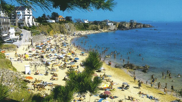 Una spiaggia affollata con molti ombrelloni e persone che si godono il mare.