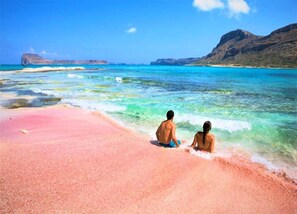 A beach with clear turquoise water, a pink sand shore, and distant rocky cliffs. - Terrace & Tranquility Home (Fresville)