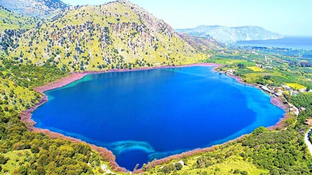 A large, clear blue lake surrounded by green hills and mountains. - Terrace & Tranquility Home (Fresville)
