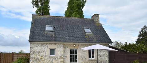 A stone house with a tiled patio, a door, and a window.