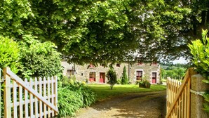 A stone building with red doors and a gravel path leading to it. - Alluring Holiday Home With Fenced Garden, Barbecue (Montaigu-les-Bois)