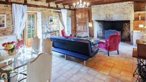 A rustic interior with exposed wooden beams, a stone fireplace, and a blue sofa. - Forest Hideaway in Saint-caprais (Saint-Caprais)