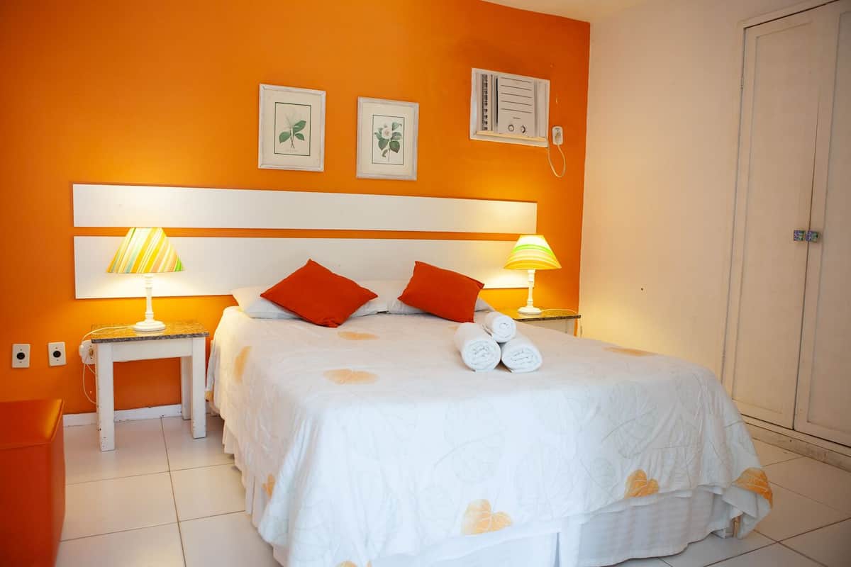 Habitación de hotel con una cama grande, dos lámparas de noche, un cabecero blanco y un armario.