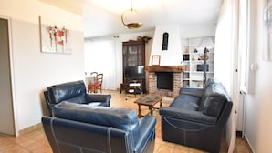 A living room with leather sofas, a fireplace, a television, and a bookshelf. - Saint-germain Beach Bliss (Saint-Germain-sur-Ay)
