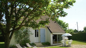 A house with a tiled roof, a door, and a small patio with a table and chairs. - Saint-germain Beach Bliss (Saint-Germain-sur-Ay)