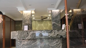 Un área de recepción con mostrador de mármol, ventilador de techo y papel tapiz estampado.