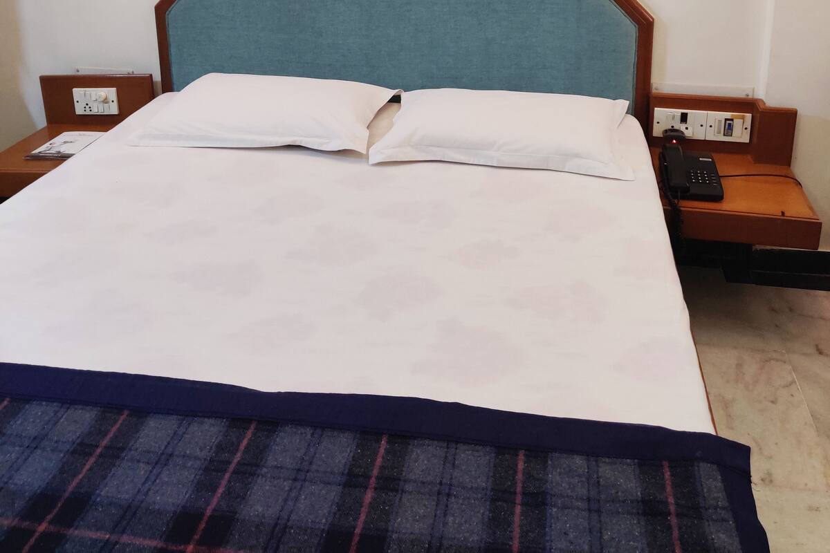 A hotel room with a bed, a bedside table, a nightstand, and a telephone.