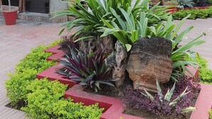 Señal del Hotel GRG con un diseño moderno, rodeado de jardines cuidados y un elemento decorativo de piedra.