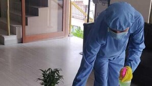 Una persona limpia una mesa de vidrio en una habitación con una escalera y una puerta que da al exterior.