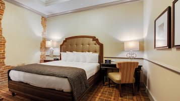 Una habitación de hotel con una cama grande, un escritorio, una silla y una lámpara.